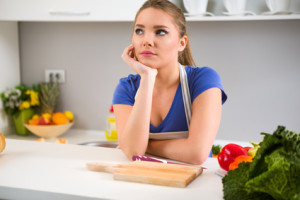 thinking young woman wondering what to cook in kitchen